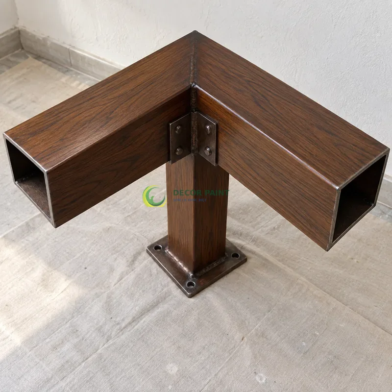 Mẫu sắt thép sơn giả gỗ óc chó sẫm, hai thanh hộp rộng nối vuông góc, góc thi công nhà ở gọn gàng, góc gần từ trên xuống của bàn thao tác.