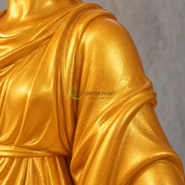 Lớp phủ vàng trên vai và nếp áo tượng làm rõ hình khối của bề mặt trang trí.