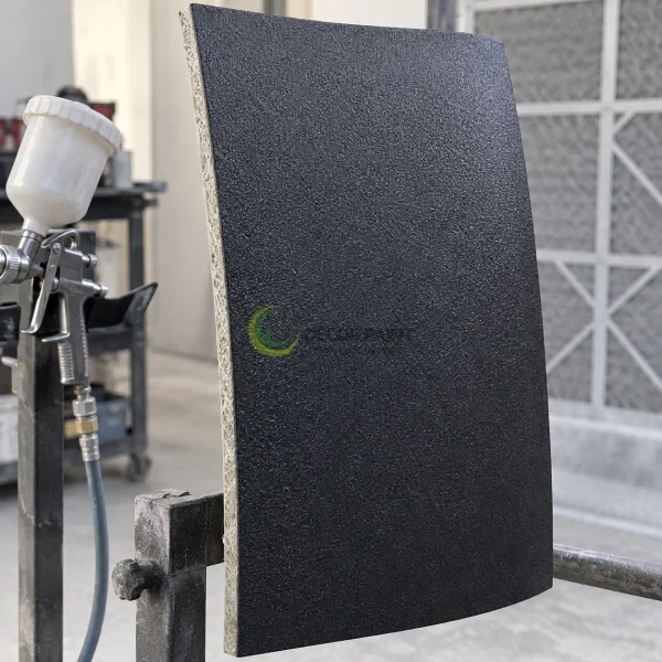 Tấm composite cong sơn nhám đen trên giá thao tác, cạnh cắt lộ vật liệu sợi.